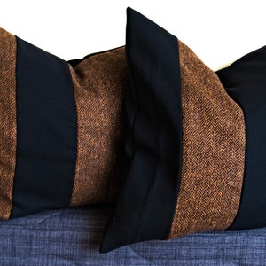 May include: Two decorative throw pillows with a brown and black herringbone pattern. The pillows are made of a soft, textured fabric.