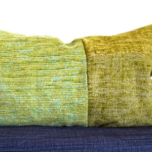 Peut inclure: Un coussin de décoration vert et vert clair avec un tissu texturé. Le coussin est posé sur une surface gris foncé.