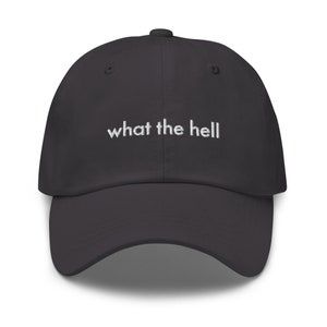 Puede incluir: Una gorra de b&eacute;isbol gris oscuro con la frase "what the hell" bordada en blanco en la parte delantera.