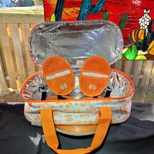 Könnte beinhalten: Orangefarbene und weiße isolierte Lunch-Tasche mit Blumenmuster und orangefarbenen Griffen. Die Tasche ist offen und hat zwei orangefarbene Stoffeinsätze im Inneren.