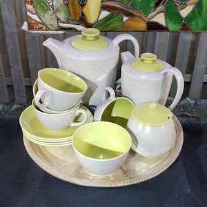 May include: A vintage tea set on a silver tray. The teapot, creamer and sugar bowl are all white with a pale green rim. The teacups and saucers are also white with a pale green rim.