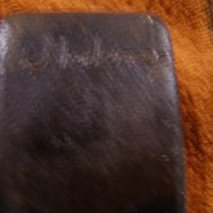 May include: Close-up of a dark brown axe head with the word "Wards" stamped on the surface.