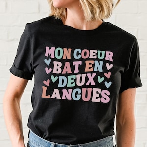 May include: Black t-shirt with the text "MON COEUR BAT EN DEUX LANGUES" in colorful letters with hearts around the words.