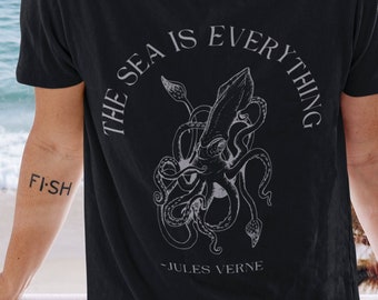 Puede incluir: Camiseta negra con un gráfico blanco de un pulpo y el texto "THE SEA IS EVERYTHING - JULES VERNE".