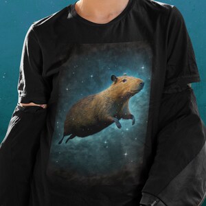 May include: A black t-shirt with a graphic of a capybara floating in space with stars in the background.