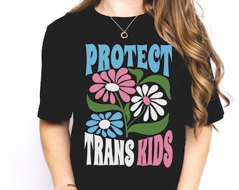 May include: Black t-shirt with the text "PROTECT TRANS KIDS" in colorful letters. The text is surrounded by three stylized flowers in pink, blue, and white.