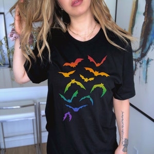 May include: A black t-shirt with a rainbow design of bats. The bats are arranged in a cluster in the center of the shirt.