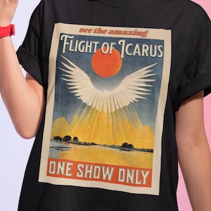 Peut inclure: T-shirt noir avec un graphique vintage d'une figure ailée volant vers un soleil rouge. Le graphique indique "See the amazing Flight of Icarus" et "One Show Only".