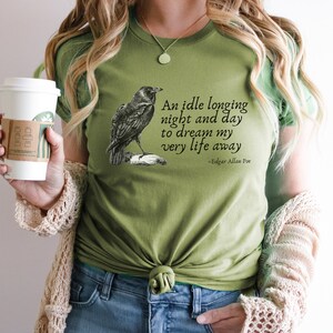 May include: Green t-shirt featuring a black raven illustration and a quote from Edgar Allan Poe: "An idle longing night and day to dream my very life away".