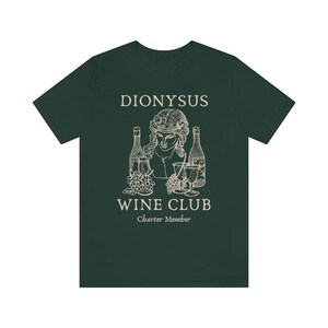 May include: A dark green t-shirt with a white graphic design of a bust of Dionysus with grapes, wine bottles, and wine glasses. The text "Dionysus Wine Club Charter Member" is printed below the graphic.