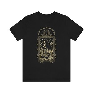 K&ouml;nnte beinhalten: Schwarzes T-Shirt mit einem goldenen Grafikdesign aus einer Bergkette, einem Halbmond, einer Sonne und einem Buch mit dem Text "Fictional Wanderlust".