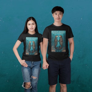 May include: Two people wearing black t-shirts with a graphic of two otters kissing underwater. The otters are brown and the background is blue with white accents.