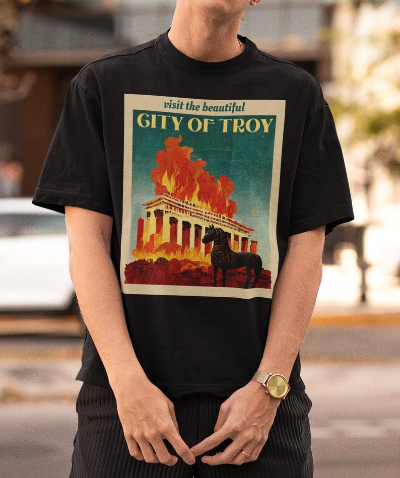 May include: Black t-shirt with a vintage travel poster design featuring a burning city and a horse. The poster reads "visit the beautiful CITY OF TROY".