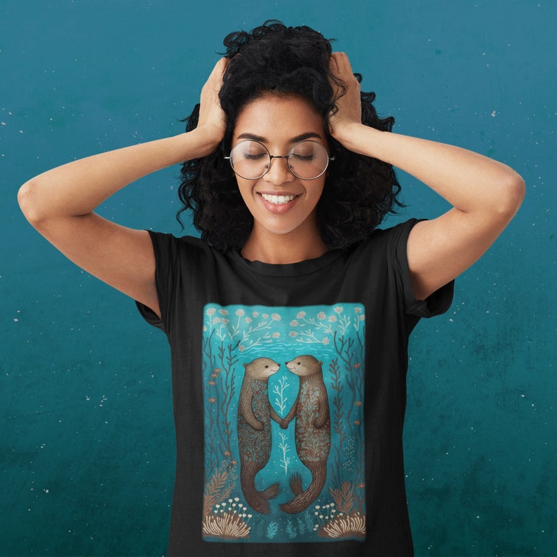 May include: Black t-shirt featuring a graphic of two otters holding hands in a blue underwater scene with coral and seaweed.