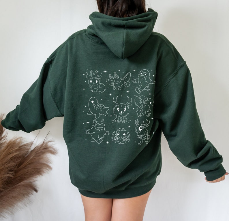 May include: A dark green hooded sweatshirt with a white outline design of various mythical creatures on the back.