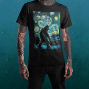 Może przedstawiać: Czarny T-shirt z nadrukiem graficznym przedstawiającym Bigfoota idącego przez nocne, gwieździste niebo, przypominające 'Gwiezdną noc' Vincenta van Gogha.