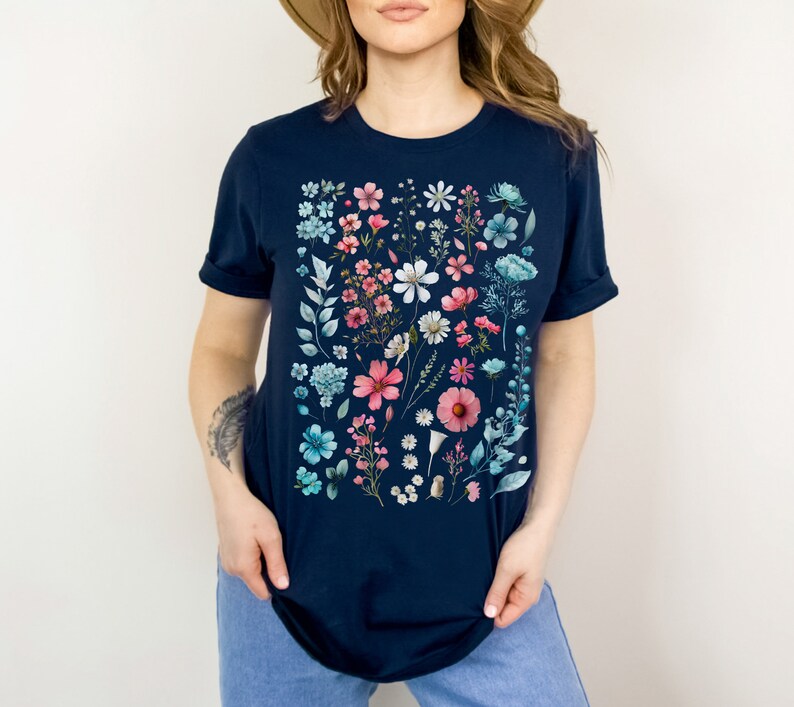 May include: A navy blue t-shirt with a colorful floral print. The print features a variety of flowers and leaves in shades of pink, blue, and white.
