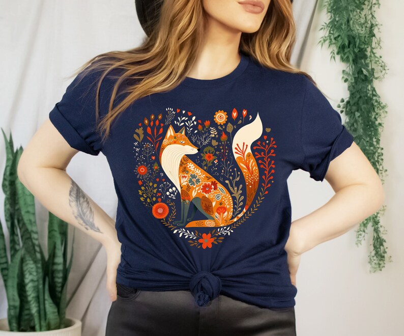 May include: A navy blue t-shirt with a graphic of a fox surrounded by flowers in a heart shape. The fox is orange and white with floral patterns on its fur.