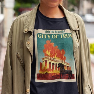May include: A black t-shirt with a vintage-style graphic of a burning city with the text "visit the beautiful CITY OF TROY" above the image.