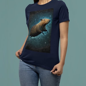 May include: A navy blue t-shirt with a graphic of a capybara floating in space with stars. The capybara is brown and has a white belly.