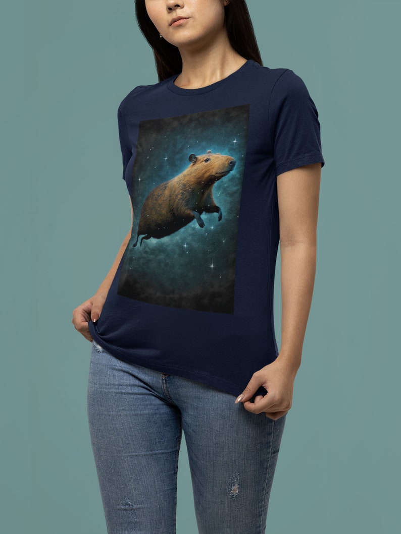 May include: A navy blue t-shirt with a graphic of a capybara floating in space with stars. The capybara is brown and has a white belly.