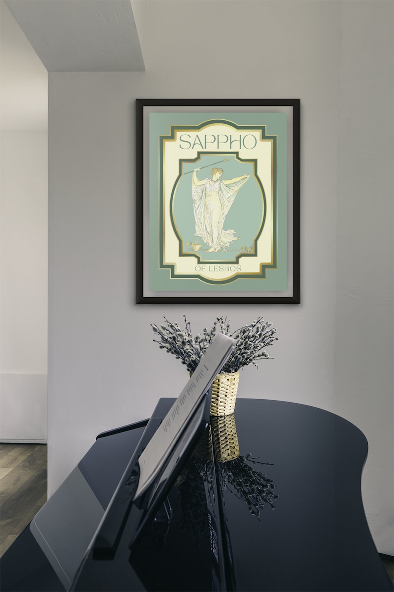 Op de afbeelding: Een ingelijste kunstdruk met de naam "Sappho" en een illustratie van een vrouw in gewaden. Het kunstwerk gebruikt een gedempte kleurenpalet van groen, cr&egrave;me en goud. Een zwarte vleugel staat op de voorgrond, met een vaas bloemen.