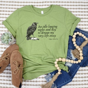May include: Green t-shirt featuring a black and white illustration of a raven and a quote from Edgar Allan Poe: "An idle longing night and day to dream my very life away".
