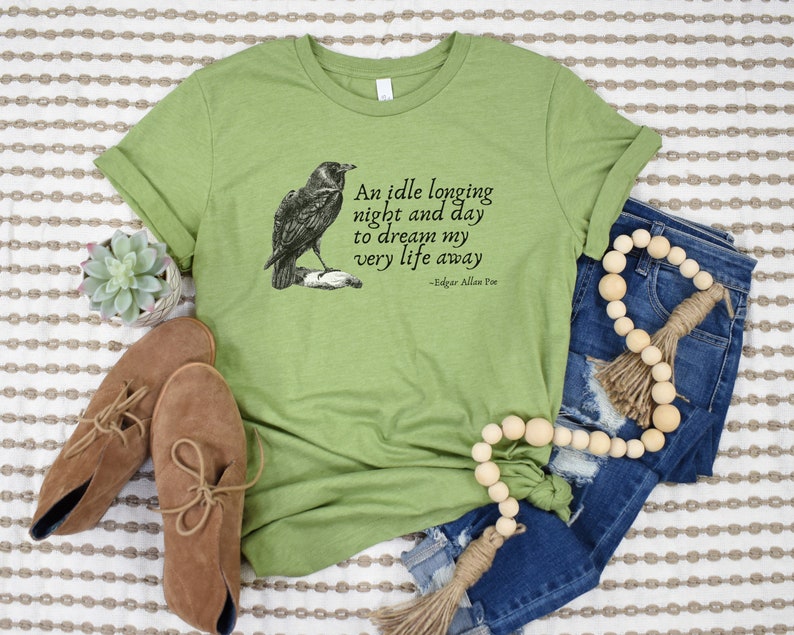 May include: Green t-shirt featuring a black and white illustration of a raven and a quote from Edgar Allan Poe: "An idle longing night and day to dream my very life away".