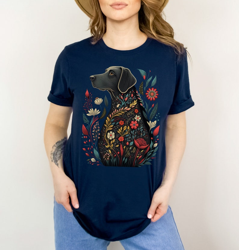 May include: A navy blue t-shirt with a black dog silhouette surrounded by colorful flowers. The dog is looking to the left and the flowers are in shades of red, yellow, orange, and green.