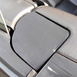 May include: Close-up of a car's interior, focusing on the black convertible top mechanism. The image shows the top's frame and surrounding trim, with visible wear and tear. The details include the top's edge and the adjacent interior panel.