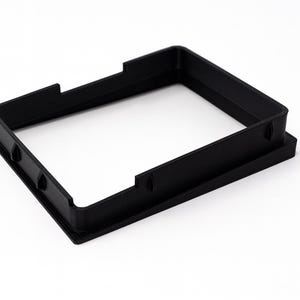May include: A black, rectangular frame with a recessed interior and a raised outer edge. The frame has cutouts on the sides and is made of a solid, matte material. The object is set against a white background.