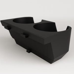 May include: A black, molded plastic car cup holder with two circular openings. The cup holder has a geometric design with mounting tabs on the sides and bottom. The overall shape is angular and modern.