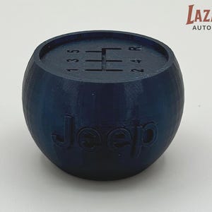 May include: A navy blue Jeep shift knob with the gear pattern 1, 3, 5, R, 2, and 4 etched on top. The word "Jeep" is embossed on the side. The product is a car part.