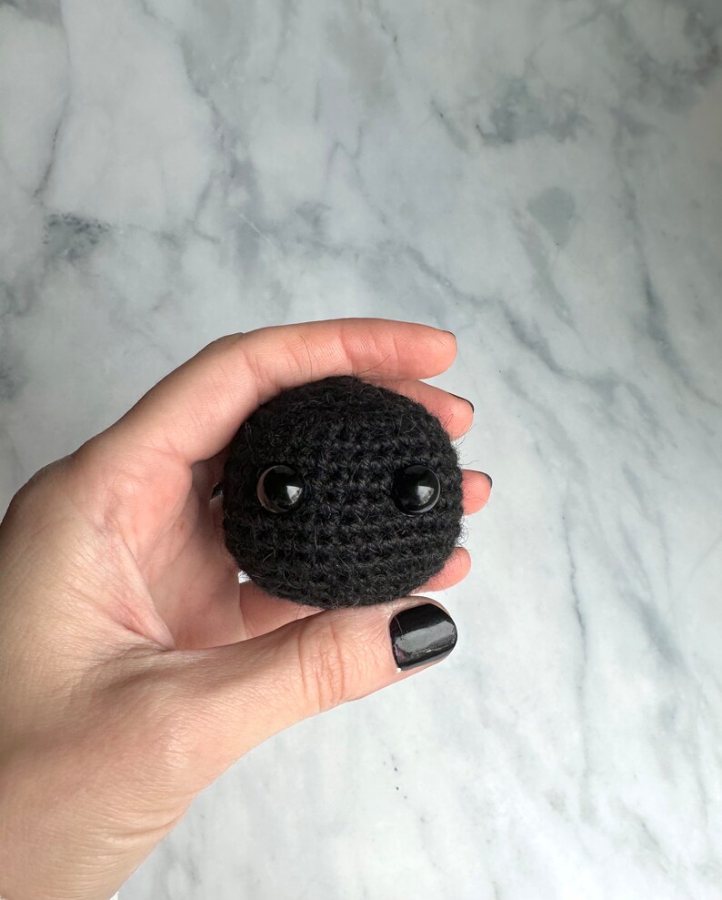Blackhole toy crocheted with yarn held in woman's hand