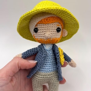 Può includere: Bambola all'uncinetto fatta a mano raffigurante Vincent van Gogh, con cappello giallo, giacca blu e pantaloni beige. La bambola ha la barba rossa e tiene un girasole giallo. La bambola è alta circa 13 cm.