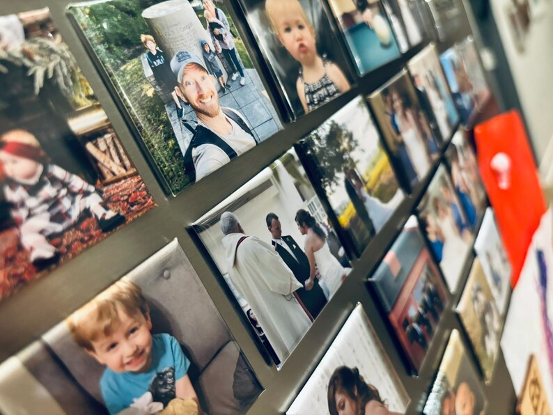May include: A collage of framed photographs on a silver surface. The photos feature a variety of subjects, including people, landscapes, and indoor scenes. Some of the photos are in color, while others are in black and white.