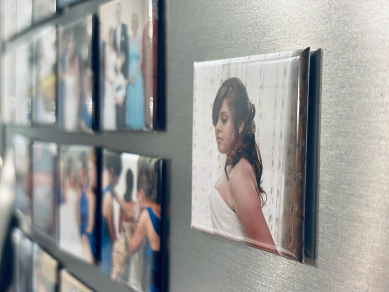 May include: A close-up of a photo magnet featuring a woman in a white dress. The photo is on a silver background with other magnets.