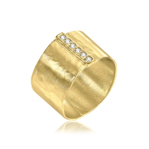 May include: A gold band ring with a row of clear stones set into the top of the band. The band is textured and has a brushed finish.