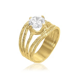 May include: A gold ring with a textured band and a large, clear, round gemstone in the center.