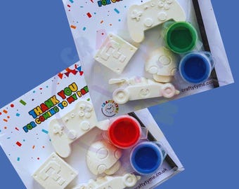 May include: Two party favor sets with a gaming theme. Each set includes a white controller, a question mark block, a mushroom, a race car, and paint pots in red, green, and blue. The packaging reads "THANK YOU FOR COMING TO MY PARTY."