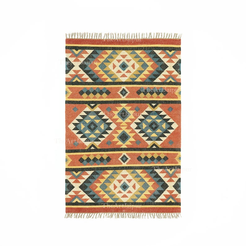 May include: Rectangular rug with a geometric pattern in shades of orange, yellow, blue, and black. The rug features a repeating diamond and triangle design, with a fringed edge. The rug is likely made of woven material.