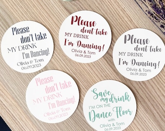 May include: Four round white coasters with black, gray, pink, and teal text. The text on the coasters reads "Please don't take my drink I'm dancing!" and "Save my drink I'm on the dance floor".