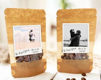 May include: Two brown paper bags with clear windows, each containing coffee beans. The windows display a Polaroid photo of a couple hugging. The bags are labeled "The Perfect Blend" with the couple's names and the date "15.07.2023".