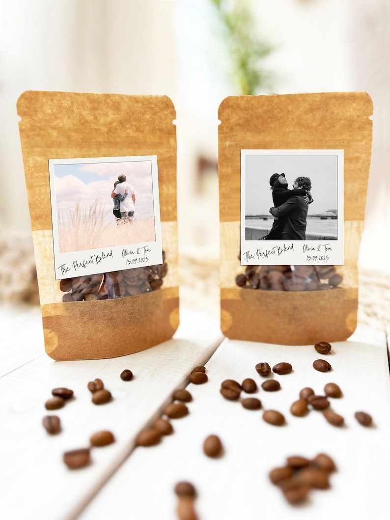 May include: Two brown paper bags with clear windows, each containing coffee beans. The windows display a Polaroid photo of a couple hugging. The bags are labeled "The Perfect Blend" with the couple's names and the date "15.07.2023".
