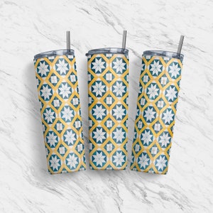 Può includere: Tre bicchieri in acciaio inossidabile con coperchi e cannucce. I bicchieri sono decorati con un motivo geometrico giallo e blu.