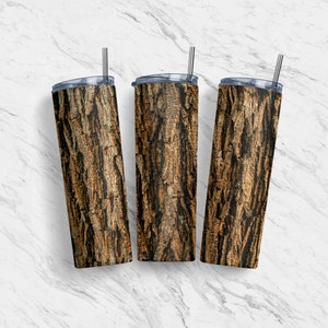 Puede incluir: Tres vasos de acero inoxidable con un patrón de corteza de árbol. Los vasos son marrones y negros con una tapa transparente y una pajita de acero inoxidable.