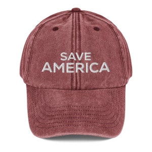 Puede incluir: Una gorra de b&eacute;isbol roja de estilo vintage con el texto "SAVE AMERICA" bordado en blanco en la parte delantera.