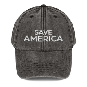 Puede incluir: Una gorra de b&eacute;isbol negra desgastada con texto blanco bordado que dice "SAVE AMERICA".