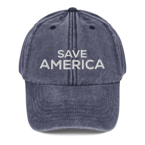 Puede incluir: Una gorra de b&eacute;isbol de mezclilla azul con el texto "SAVE AMERICA" bordado en blanco en la parte delantera.