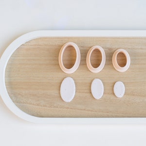 May include: A set of four wooden oval cookie cutters in various sizes, with three matching fondant cutouts on a wooden tray.